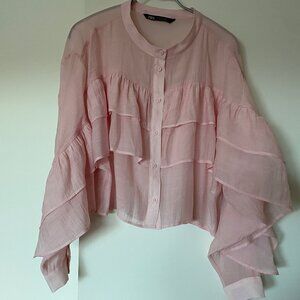 Blouse à volants rose pale légèrement transparente